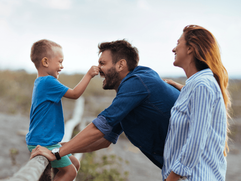 Laughing family with father, mother, and child having fun together in nature.