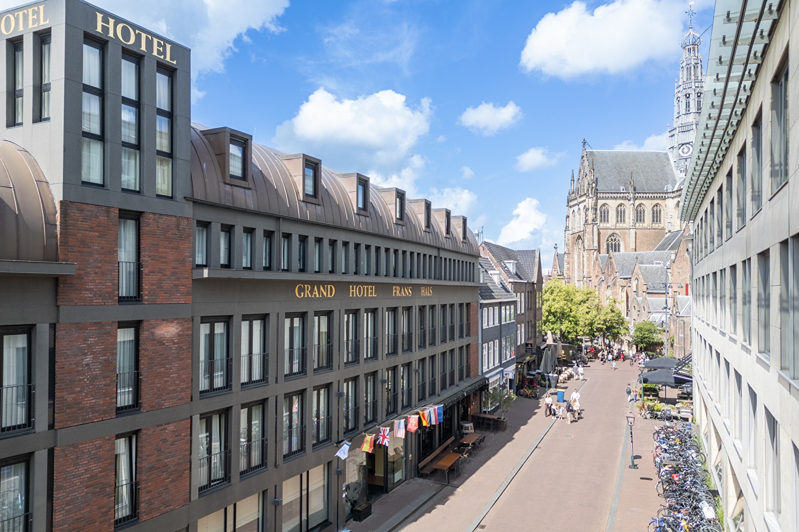 Amrâth Grand Hotel Frans Hals in Haarlem met op de achtergrond de Grote Kerk, moderne gevel met klassieke omgeving.