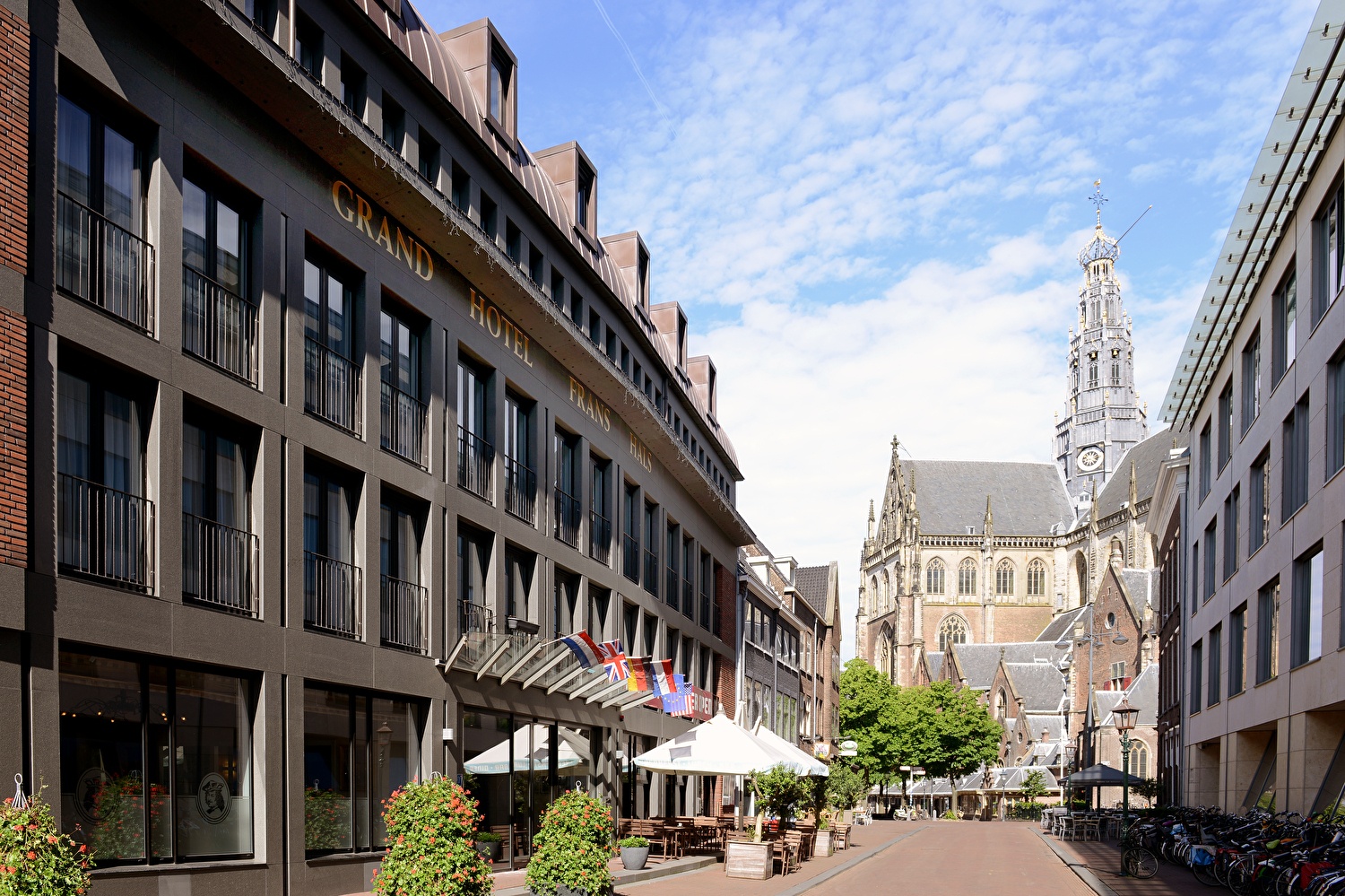 Amrâth Grand Hotel Frans Hals in Haarlem met op de achtergrond de Grote Kerk, moderne gevel met klassieke omgeving.