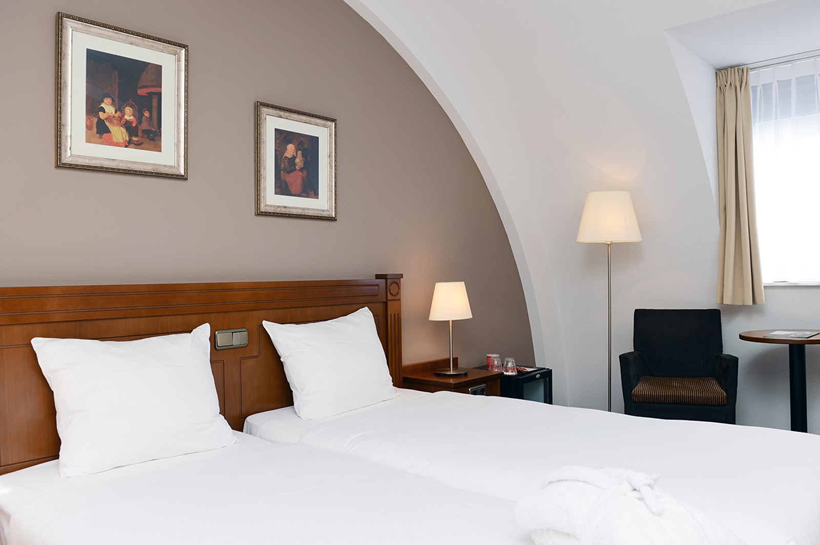 Deluxe kamer in Amrâth Grand Hotel Frans Hals met twee comfortabele eenpersoonsbedden, warme houten accenten, moderne verlichting en een zitgedeelte bij het raam.