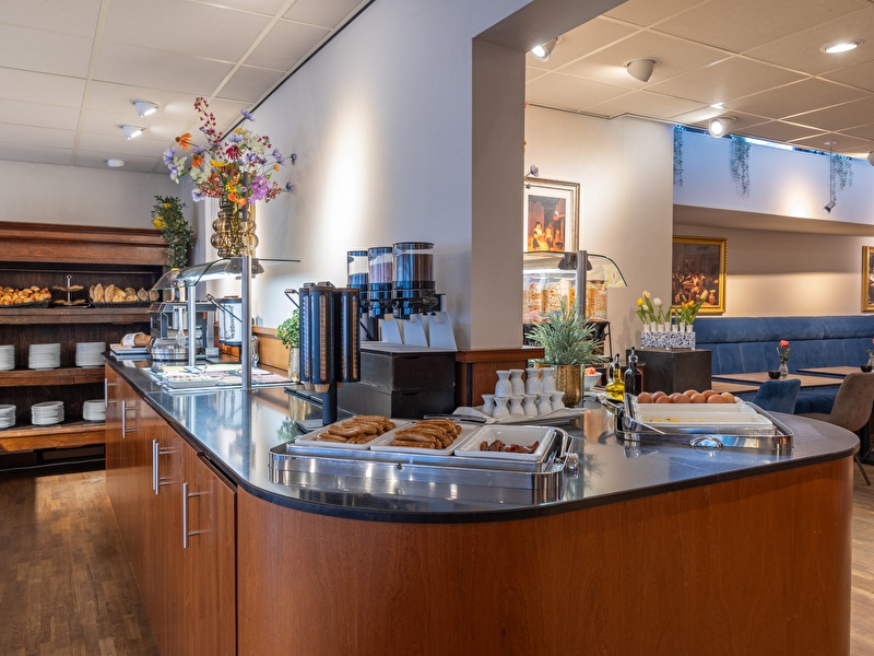 Ein Frühstücksteller mit Croissants, Brot, Aufschnitt, Lachs, einem gekochten Ei, Orangensaft und Tee im Amrâth Grand Hotel Frans Hals.